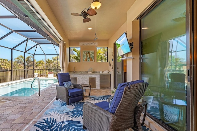 view of patio / terrace with glass enclosure, ceiling fan, a fenced in pool, and exterior kitchen