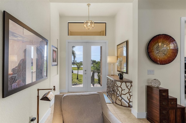 tiled entrance foyer with a chandelier, french doors, and baseboards