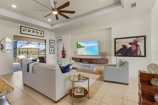 living area with a raised ceiling, visible vents, baseboards, and light tile patterned floors