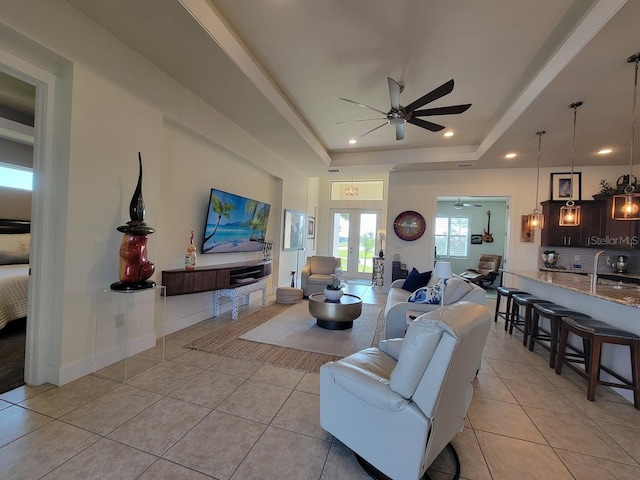 living room with light tile patterned floors, ceiling fan, a raised ceiling, and french doors