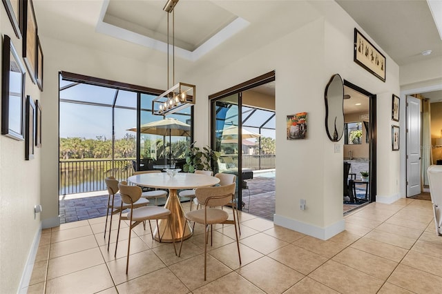 dining area with light tile patterned floors, baseboards, a raised ceiling, and a sunroom