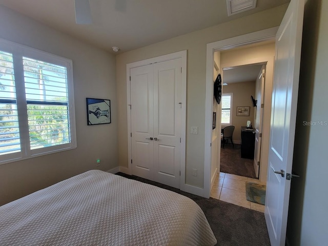 carpeted bedroom with tile patterned flooring, a closet, visible vents, and baseboards