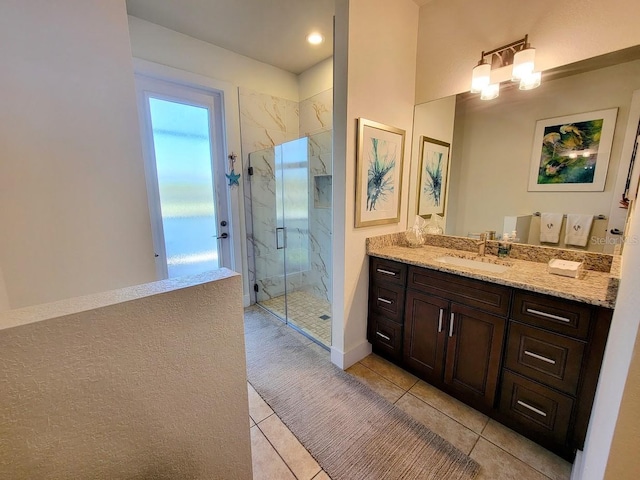 bathroom featuring tile patterned flooring, a marble finish shower, and vanity