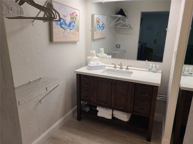 bathroom featuring vanity, a textured wall, and baseboards