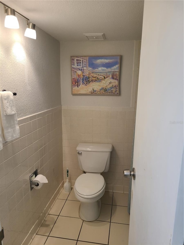 bathroom featuring tile patterned floors, visible vents, toilet, and a textured ceiling