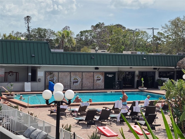 community pool with a patio area and fence