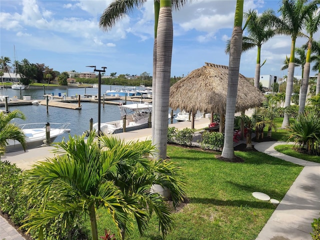 view of home's community with a water view, a lawn, and a boat dock