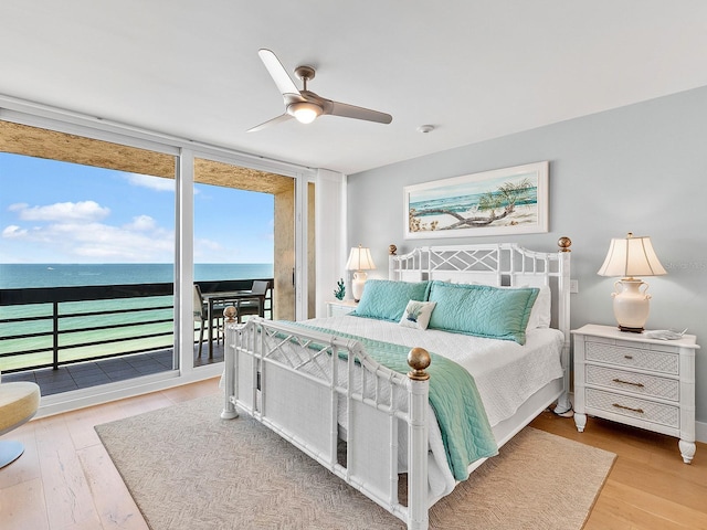 bedroom featuring expansive windows, ceiling fan, wood finished floors, and access to exterior