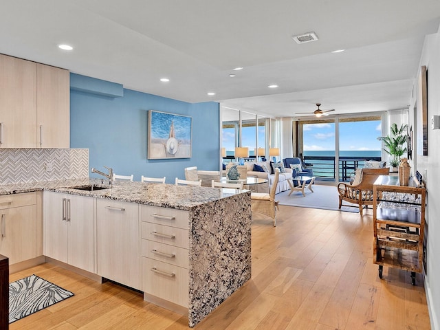 kitchen with a sink, visible vents, a peninsula, and light wood-style flooring