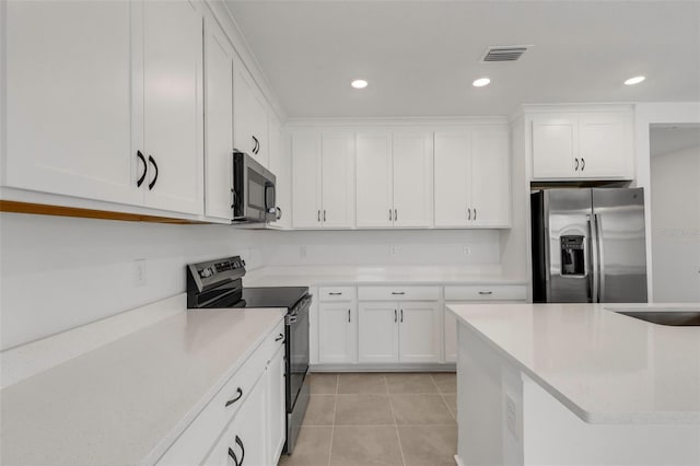 kitchen featuring light tile patterned floors, stainless steel appliances, visible vents, white cabinetry, and a sink