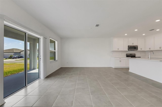 kitchen with a sink, white cabinets, light countertops, appliances with stainless steel finishes, and backsplash