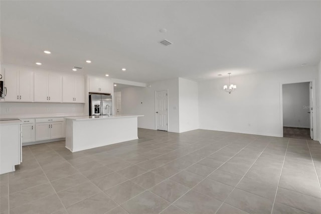 kitchen featuring light countertops, visible vents, open floor plan, white cabinetry, and stainless steel fridge