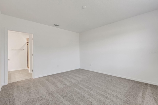 carpeted spare room featuring visible vents and baseboards