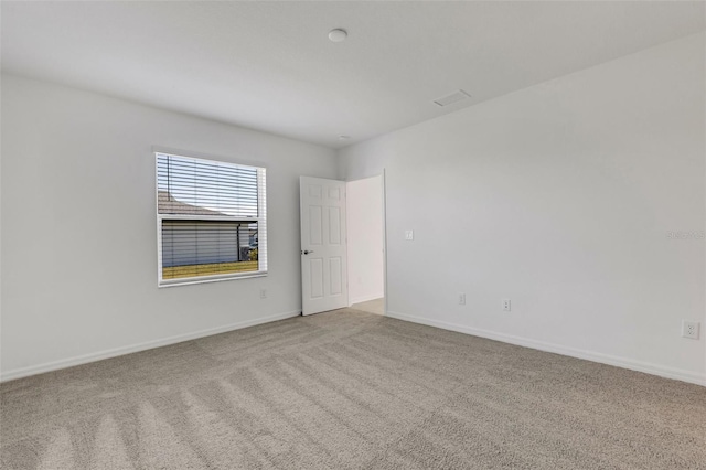 carpeted spare room featuring baseboards