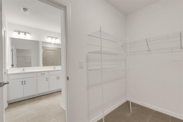 walk in closet featuring visible vents, a sink, and light tile patterned floors