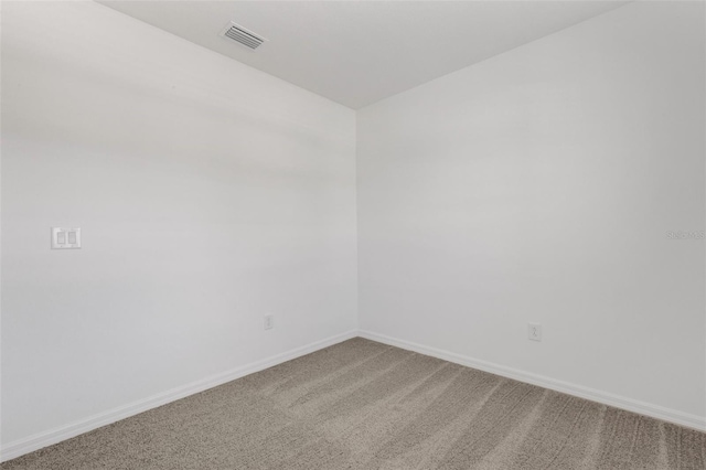 spare room featuring carpet floors, visible vents, and baseboards