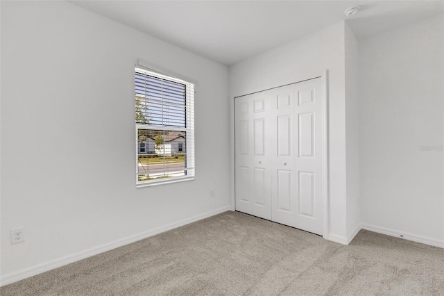 unfurnished bedroom with a closet, carpet flooring, and baseboards