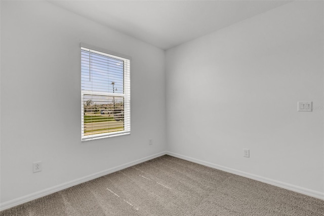 carpeted empty room featuring baseboards