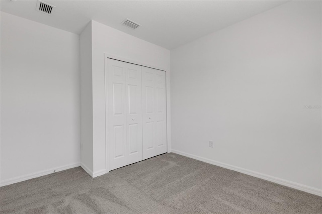 unfurnished bedroom with baseboards, a closet, visible vents, and carpet flooring