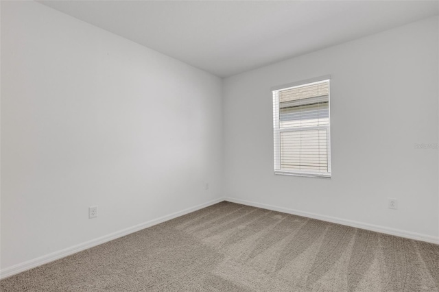 carpeted empty room featuring baseboards