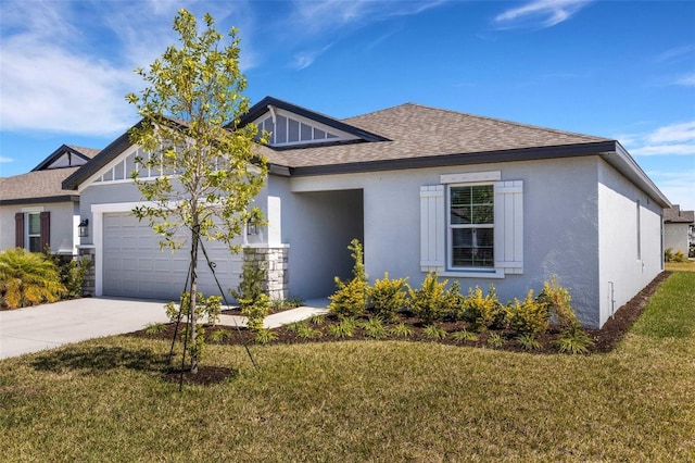 view of front of home featuring an attached garage, a shingled roof, concrete driveway, and a front yard