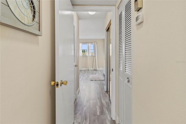 corridor featuring wood finished floors and baseboards