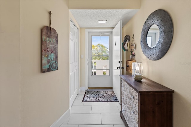 entryway with light tile patterned floors, baseboards, and a textured ceiling