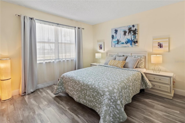 bedroom with a textured ceiling, baseboards, and wood finished floors