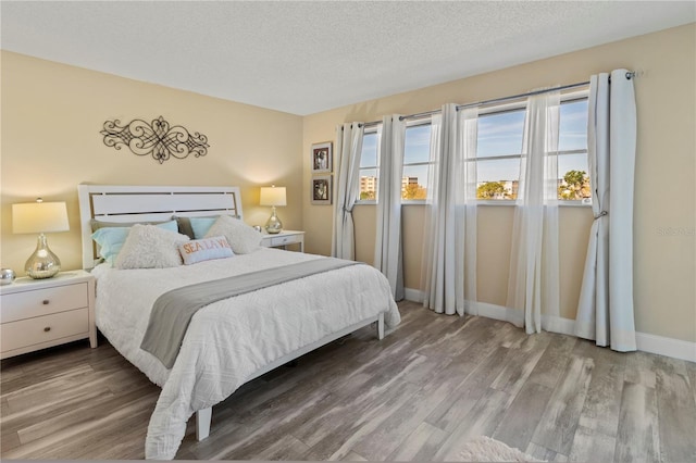 bedroom with a textured ceiling, baseboards, and wood finished floors