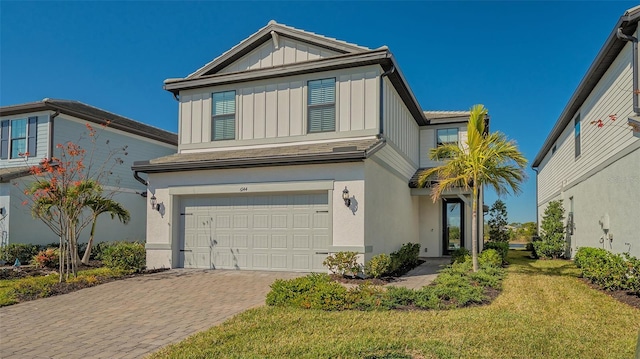 view of front of house featuring a garage, decorative driveway, a front lawn, board and batten siding, and stucco siding