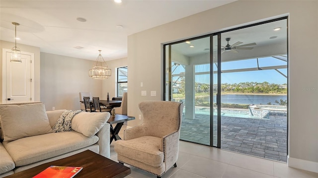 living room featuring ceiling fan with notable chandelier, recessed lighting, a water view, and light tile patterned flooring