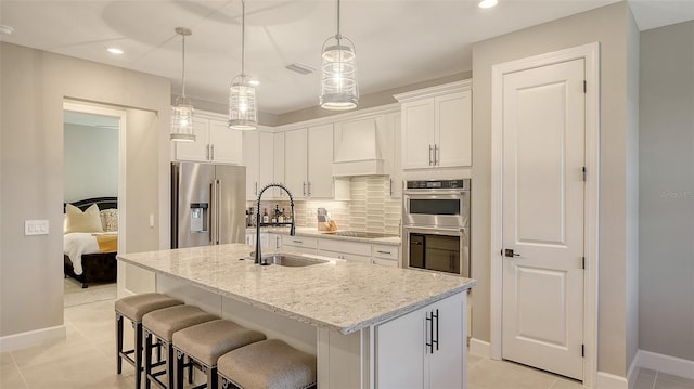 kitchen with tasteful backsplash, visible vents, stainless steel appliances, premium range hood, and a sink