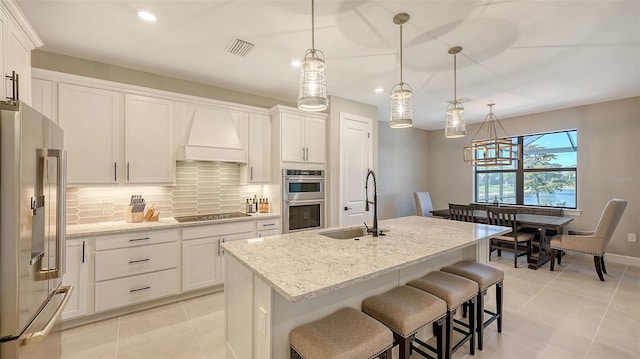 kitchen featuring premium range hood, a sink, white cabinets, appliances with stainless steel finishes, and tasteful backsplash