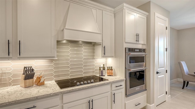 kitchen featuring double oven, black electric stovetop, white cabinets, tasteful backsplash, and custom range hood