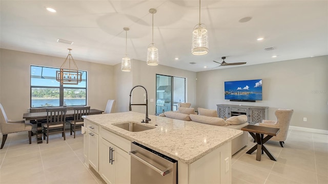 kitchen featuring light tile patterned floors, dishwasher, an island with sink, decorative light fixtures, and a sink