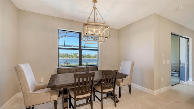 dining room with light tile patterned floors, a water view, an inviting chandelier, and baseboards