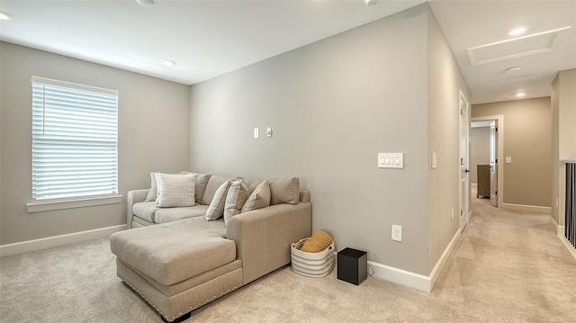 carpeted living room with attic access and baseboards