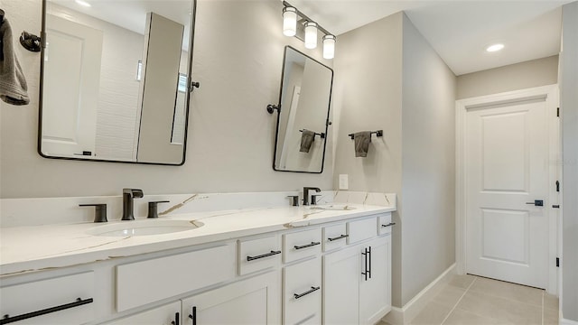 full bath featuring double vanity, a sink, baseboards, and tile patterned floors