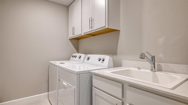 laundry room featuring cabinet space, baseboards, separate washer and dryer, and a sink