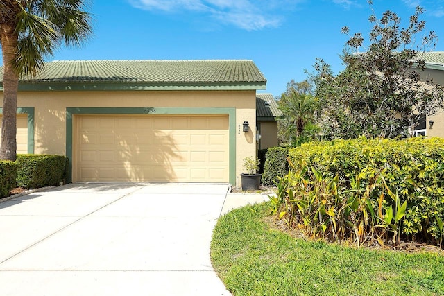 view of front of home featuring a garage, concrete driveway, a tiled roof, and stucco siding