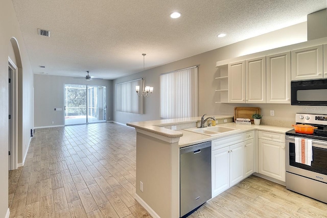 kitchen featuring stainless steel appliances, light wood-style floors, a sink, and a peninsula