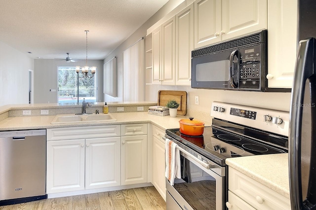 kitchen with appliances with stainless steel finishes, a peninsula, a textured ceiling, a chandelier, and a sink