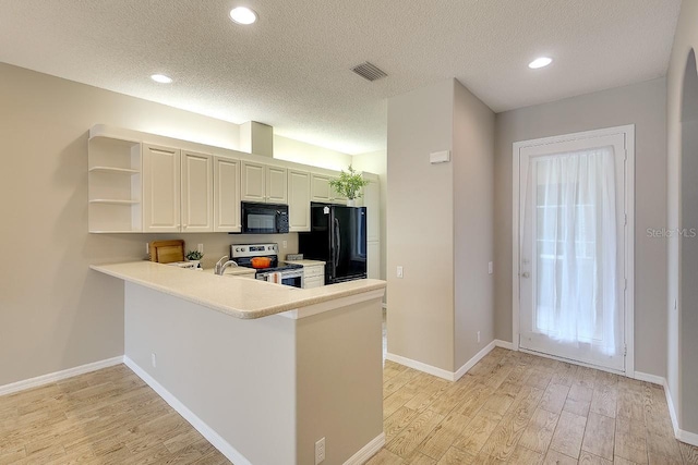 kitchen featuring light wood-style flooring, a peninsula, open shelves, light countertops, and black appliances