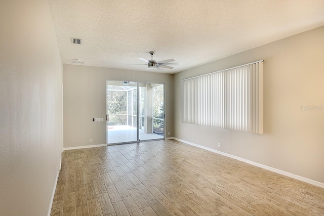 empty room with a ceiling fan, a textured ceiling, baseboards, and wood finished floors