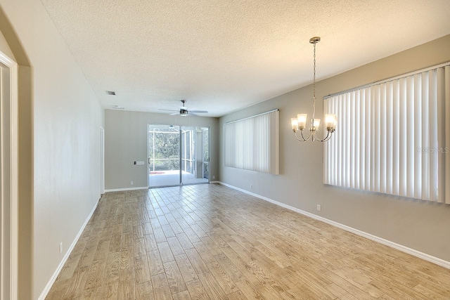 spare room featuring light wood-type flooring, baseboards, a textured ceiling, and ceiling fan with notable chandelier