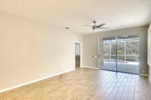 spare room with light wood-style floors, ceiling fan, baseboards, and a textured ceiling