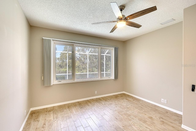 empty room featuring visible vents, a textured ceiling, baseboards, and wood finished floors