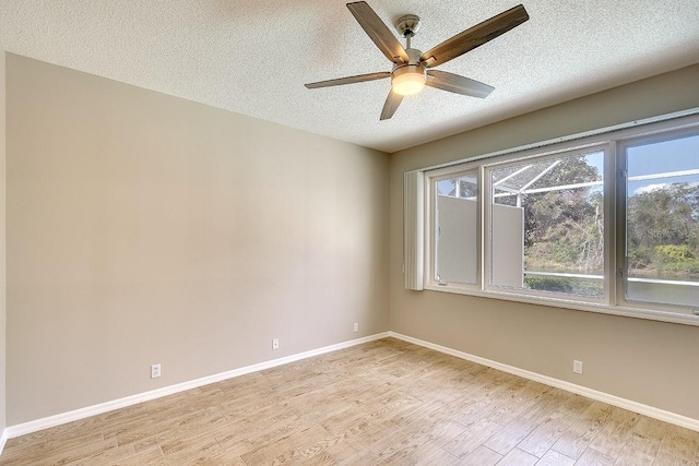 empty room featuring light wood-type flooring, a ceiling fan, baseboards, and a textured ceiling