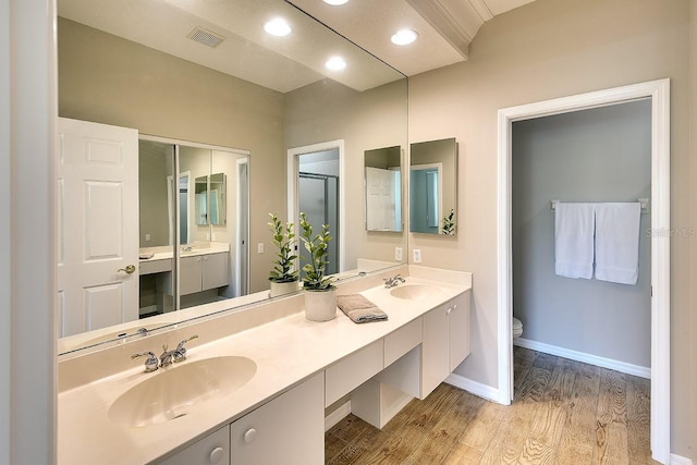 bathroom featuring double vanity, visible vents, a sink, and wood finished floors