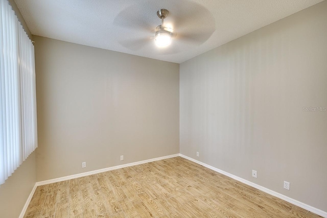 spare room with baseboards, a textured ceiling, a ceiling fan, and light wood-style floors